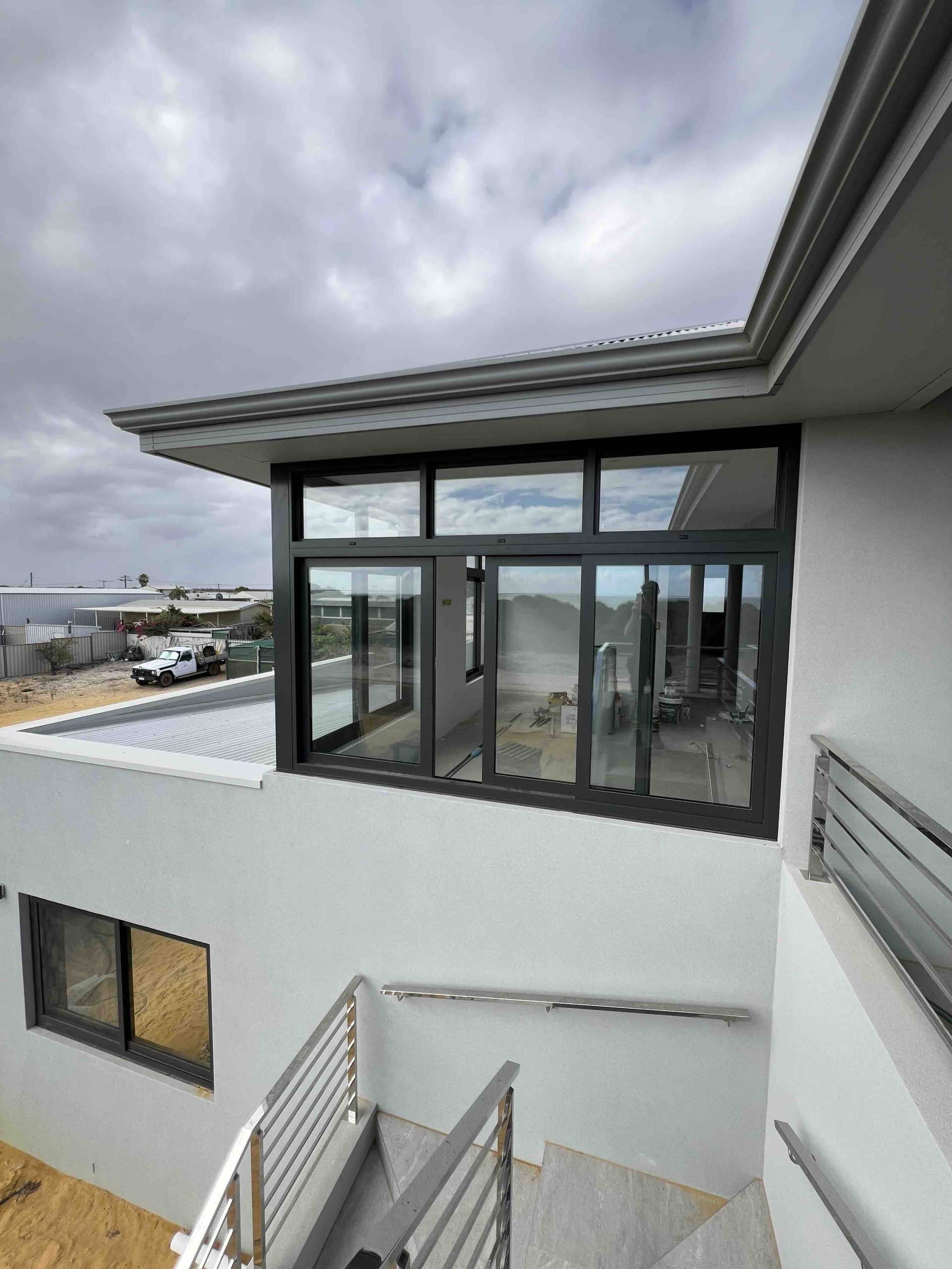 Anthracite thermally broken aluminium stacker doors with highlight windows installed on upper level Perth home by Penot Double Glazing, double glazed for energy efficiency and wind resistance.